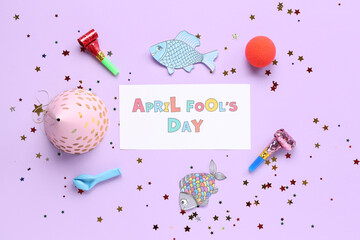 Festive postcard for April Fools Day with paper fishes and party decor on lilac background
