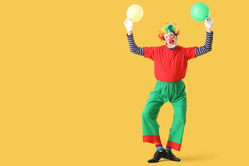 Portrait of clown with balloons on yellow background. April Fool's day celebration