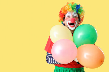 Portrait of clown with balloons on yellow background. April Fool's day celebration