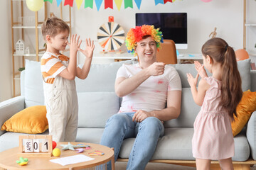 Little children pranked their father with colorful clown wig at home. April Fool's Day prank