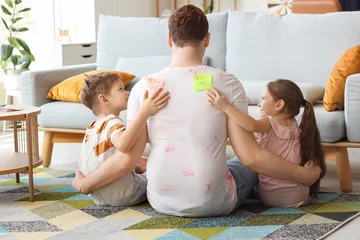 Gardinen Little children sticking KICK ME stickers to their father's back at home. April Fool's Day prank © Pixel-Shot
