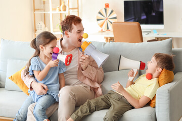 Father and his children with megaphones at home. April Fool's Day prank