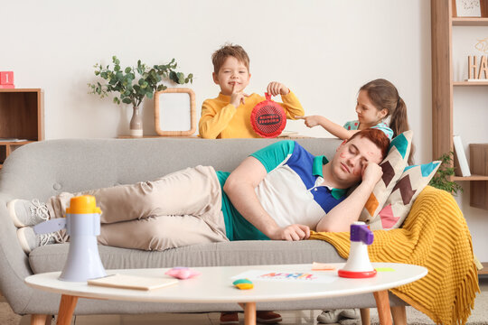 Little children planning to prank their sleeping father with whoopee cushion at home. April Fool's Day prank