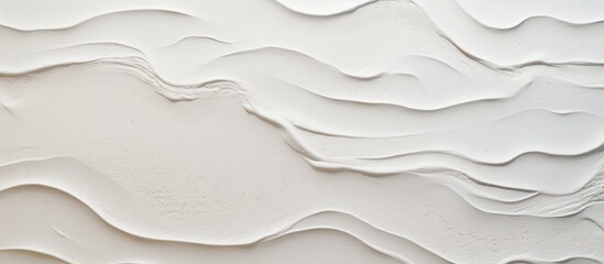 A closeup of a grey landscape with a circle pattern on a white wall. The waves create a mesmerizing gesture, resembling a sleeve of paper with a unique font