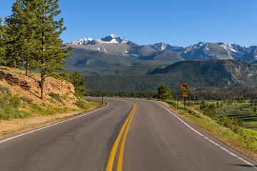 Fototapeta na wymiar U.S. Route 36 in RMNP - A Spring evening view of winding Highway 36, with snow-capped Longs Peak towering in background, in Rocky Mountain National Park, Colorado, USA.