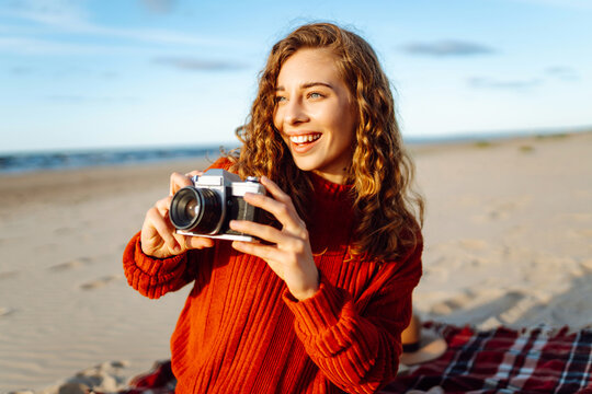 Young woman walking at the beach and taking photos captures the beauty of nature. Travel blog. Adventure, vacation concept.