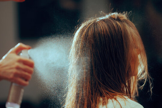 Hairdresser Spraying a Hair Styling Product on Client Hair. High quality salon services using a heat protective product before heat styling 
