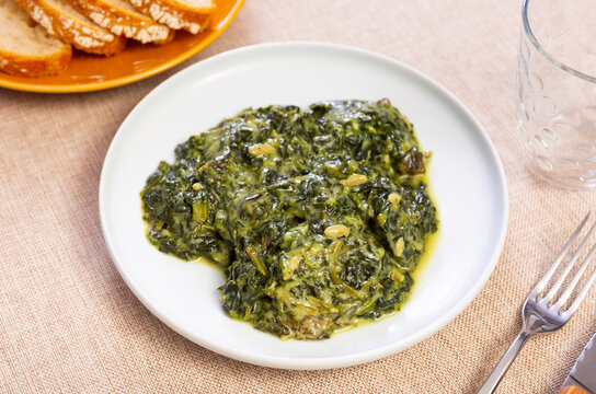 There is portion of dietary side dish on plate - Catalan spinach. Dish is steamed, with addition of raisins, pine nuts and spices. Optionally complemented with fried toasts