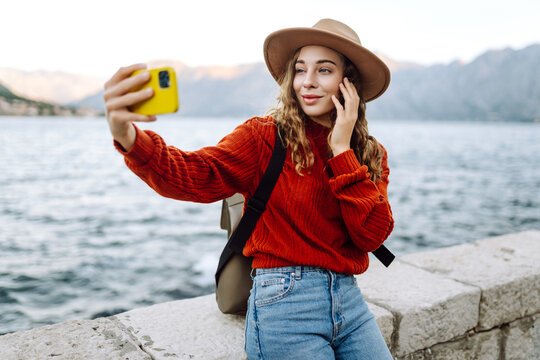 Happy woman in autumn clothes making selfie on smartphone outdoors. Stylish woman with phone. Concept of vacation, technology, weekend.