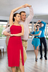 Group of different ages active people in festive clothes dancing dance movements in modern studio