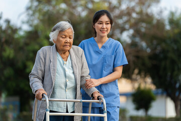 caregiver nurse support senior woman walking with walker in park