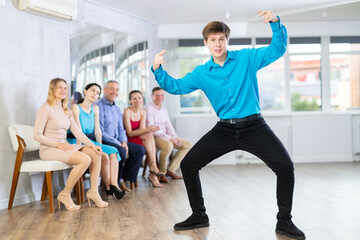 Fototapeta na wymiar Young guy shows various dance hip hop moves at a dance lesson in the studio