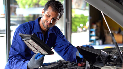 happy latin auto mechanic man checking and repairing or change air filter box in garage cars...
