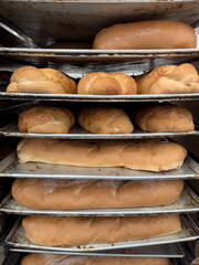 Various metal shelves with fresh, golden breads. There are different types of bread freshly baked. Irresistible Aroma, Unparalleled Flavor of freshly baked bread. Fresh bread daily