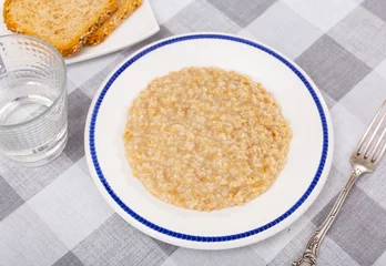Fotobehang Appetizing milk oatmeal porridge served on plate for breakfast © JackF