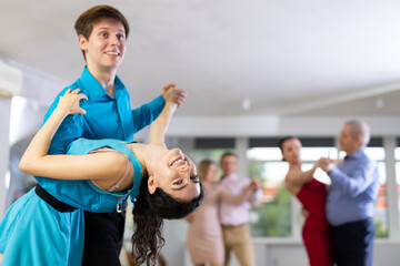 In dynamic salsa dance class, positive young couple in elegant attire skillfully performing dip...