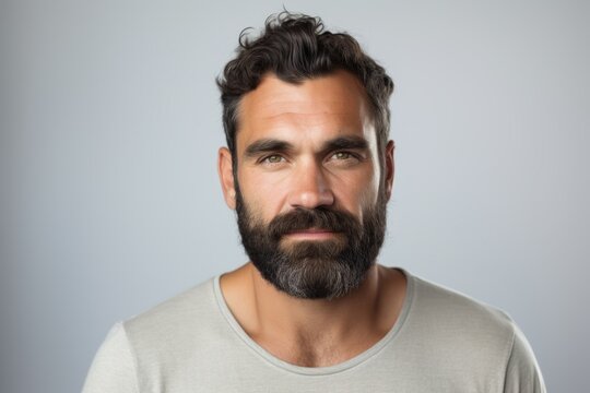 Handsome man with beard and mustache looking at camera over grey background