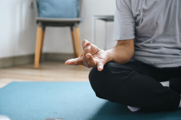 Hand of man doing yoga or gyan mudra symbol and meditating at home