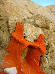 Close up of sand and the old red house bricks weathered by decades of sea power and weather at the beach 