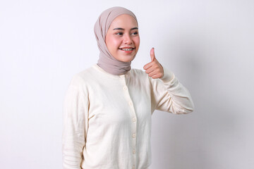 Young Asian moslem woman with braces and hijab showing thumbs up with happy expression
