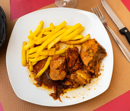 Pollo rustido in Catalan - baked chicken flavored with oregano, white wine, sweet wine, grapes, prunes. Served with French fries