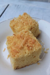 Slices of Indonesian food called prol tape sprinkled with cheese in a white plate on the table