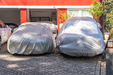 Two covered cars on a yard in front of the garage door. Car Cover Carport Parking