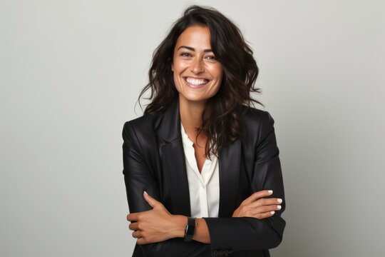 Portrait of a smiling businesswoman with arms crossed against grey background