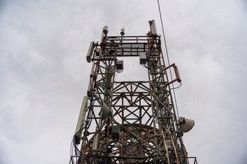 A complex web of antennas and equipment adorns this towering communication structure, stark against the grey, overcast sky. The technological might of this facility is underscored by the gloomy weathe