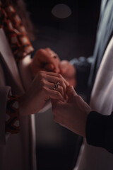 Two hands are intimately linked, with a focus on the engagement ring, symbolizing a bond of love and commitment in a tender moment.