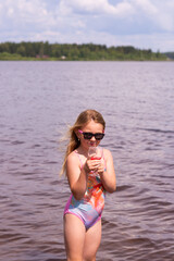 On a hot summer day, a child is relaxing on the lake. A girl on the beach. A girl swims on an inflatable pink flamingo and drinks delicious fresh juice.