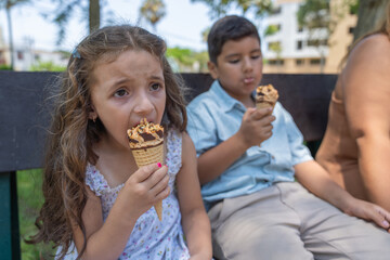 Latin schoolgirl and boy eating ice cream in a park