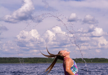 The girl frolics in the water on a hot sunny summer day and is happy.