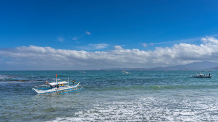 A traditional Filipino   boat bangka with a double-outrigger dugout bobs on the waves of the...