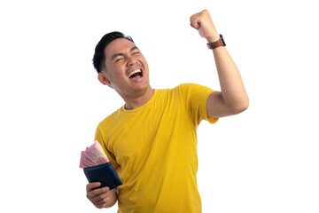 Excited handsome Asian man holding cash in wallet and raising fist up isolated on white background