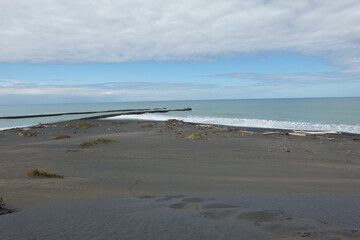 Footsteps leading down black sand-dunes to waters edge.