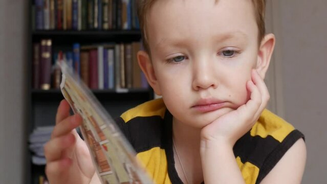 Close-up of the face of a cute little boy watching a comic book