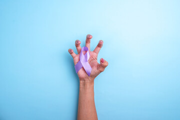 Purple ribbon on cramped hand isolated on blue background.
