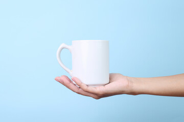 Hands Holding White Ceramic Mug for Mockup Isolated on Blue Background