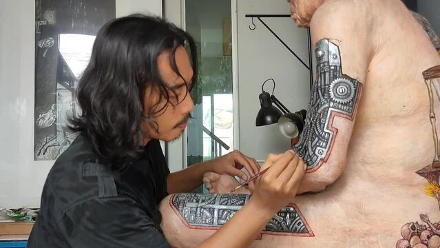 Artist painting cyberpunk art on human sculpture.