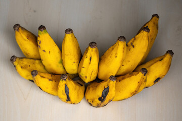 A bunch of fresh ripe bananas on a wooden background. Bananas are a nutritious fruit that has many health benefits.  - obrazy, fototapety, plakaty