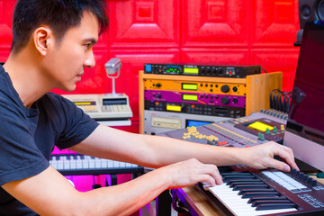asian handsome professional music producer arranging a hit song on computer by midi keyboard in home studio - 758575370