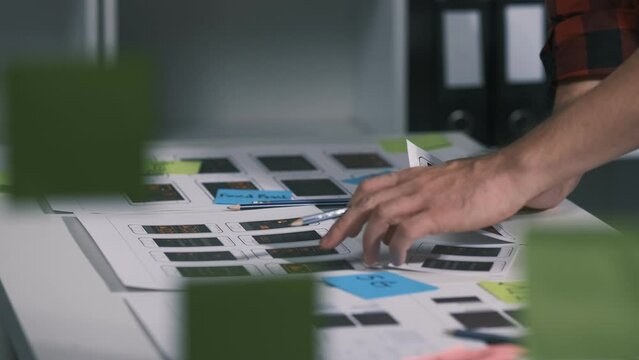 An employee is planning an event in a conference room with documents scattered across the table before preparing to present it in front of his co-workers and boss.