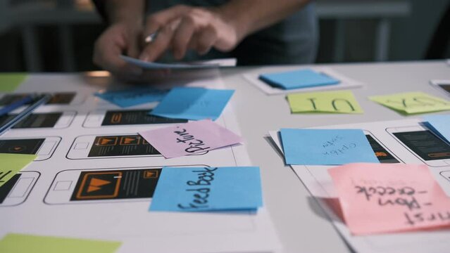 An employee is planning an event in a conference room with documents scattered across the table before preparing to present it in front of his co-workers and boss.