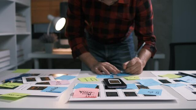 An employee is planning an event in a conference room with documents scattered across the table before preparing to present it in front of his co-workers and boss.