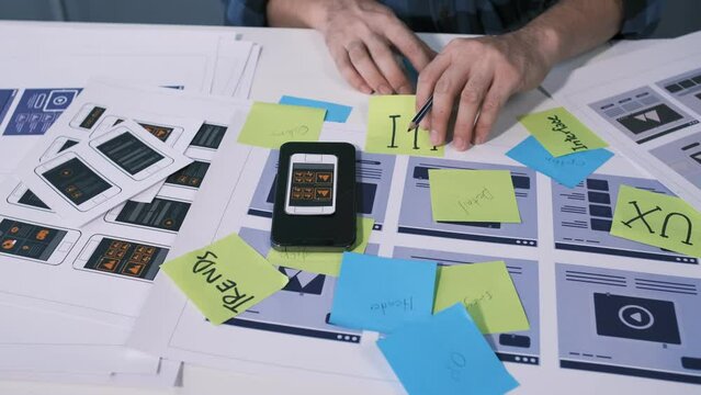 An employee is planning an event in a conference room with documents scattered across the table before preparing to present it in front of his co-workers and boss.