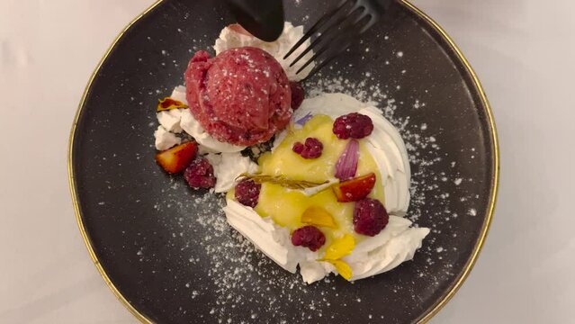 A sweet dessert with ice cream and fresh fruit eaten with cutlery