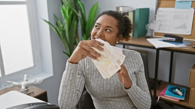 African american woman with curly hair holding turkish lira in a modern office interior