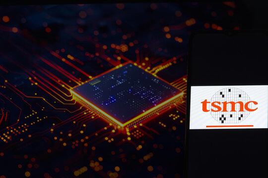 TSMC (Taiwan Semiconductor Manufacturing Company Limited) logo on a smartphone screen, AI computer chip in the background.