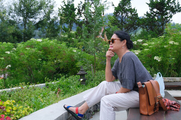 Woman sitting alone in the park contemplating with right hand supporting her chin